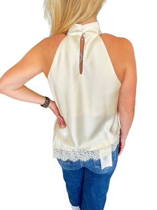 Solid sleeveless high neck top featuring asymmetric lace hem