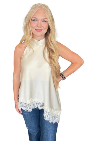 Solid sleeveless high neck top featuring asymmetric lace hem
