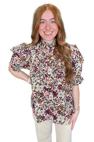 Floral print short puff sleeve top featuring ruffled neckline detail. Button closure at front